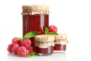 jars with jam and ripe raspberries with mint isolated on white